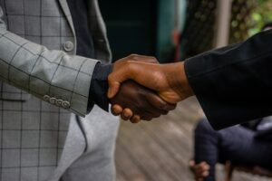 A person wearing a gray suit jacket is shaking hands with a person