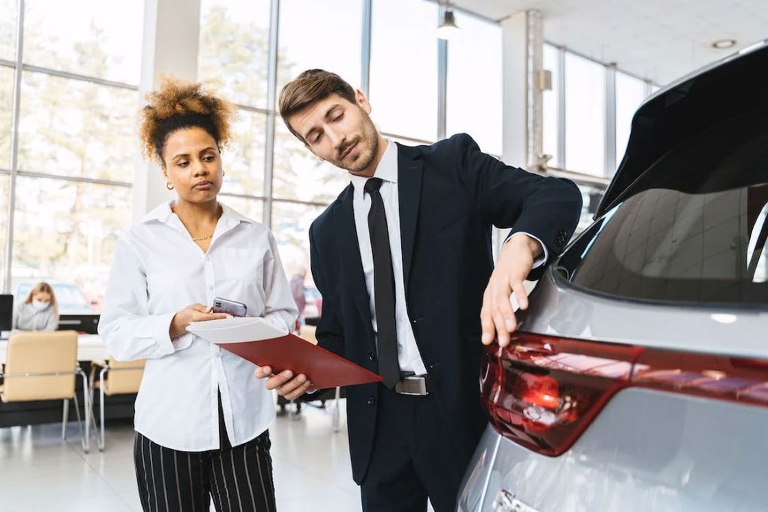 Salesman talking to a customer about the features of a new car