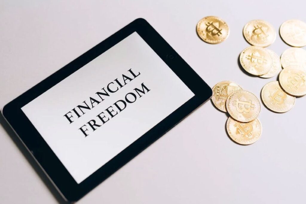 Tablet with a text Financial Freedom on its white screen with coins beside it