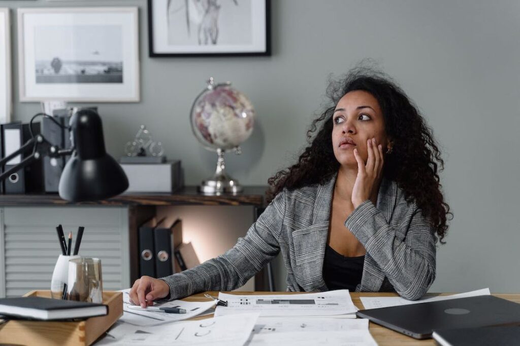 Woman with her hands on her face staring into space while sitting in her office