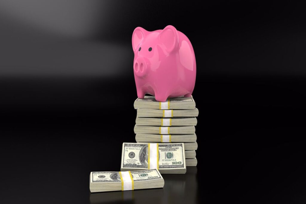 Pink piggy bank sitting on stacked dollar bills