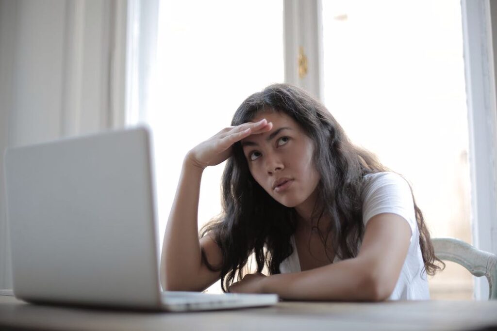 Woman staring into space while her laptop is on the table