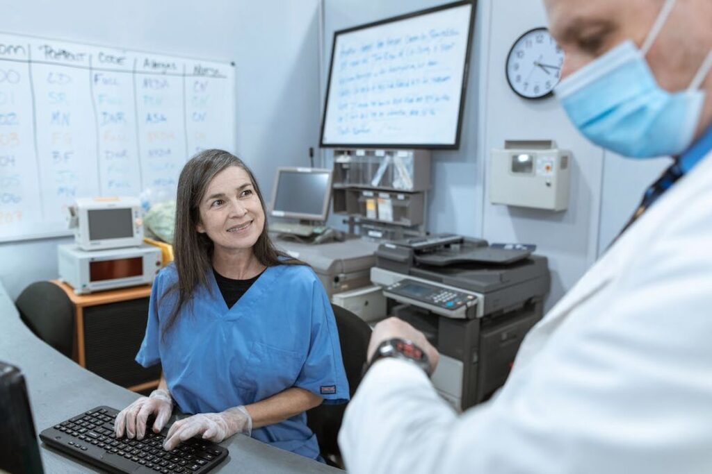 Nurse talking to a doctor while typing on a computer