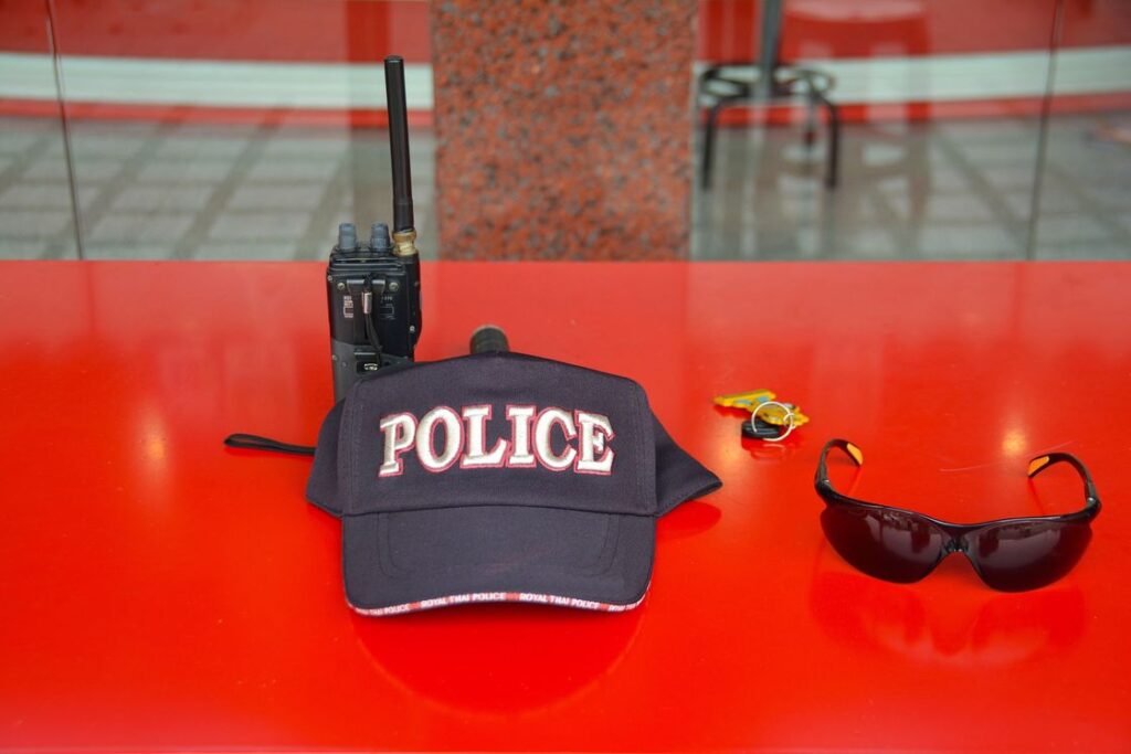 Police cap, sunglasses, radio and keys are placed together on a red table