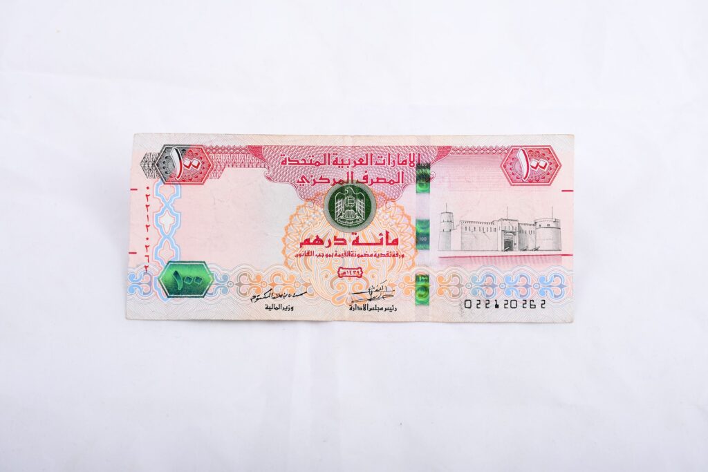 A 100 United Arab Emirates dirham bill was placed on a white surface