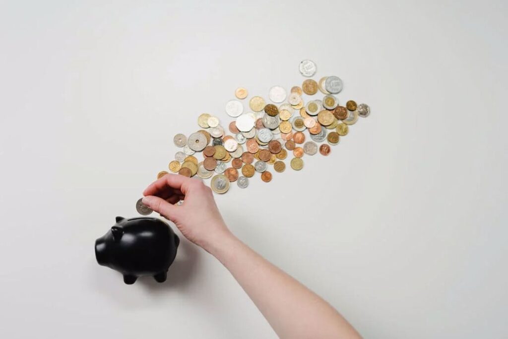 Person putting coins in a black piggy bank