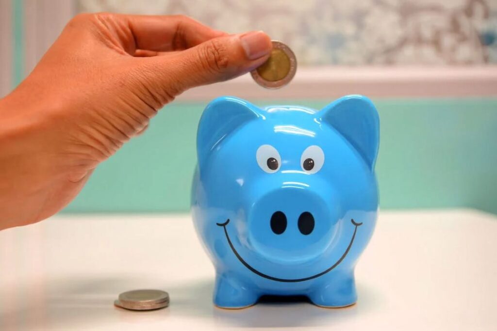 Person putting coins on a blue piggybank