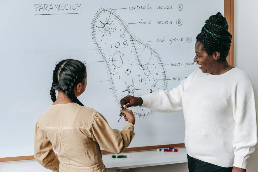 A woman in white long-sleeves and black pants teaching her student about Paramecium