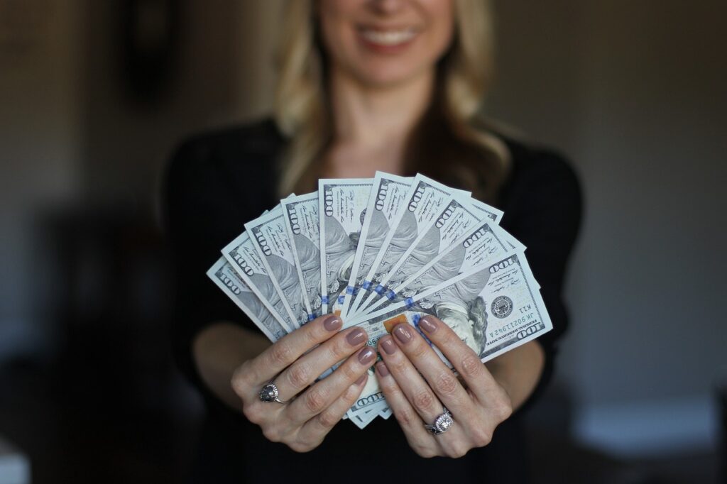 A woman in a black blouse holding US dollar bills in 100