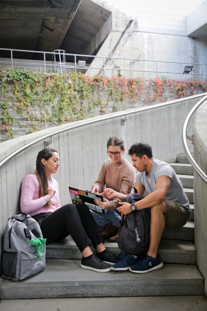 A group of students studying in the staircase with a laptop