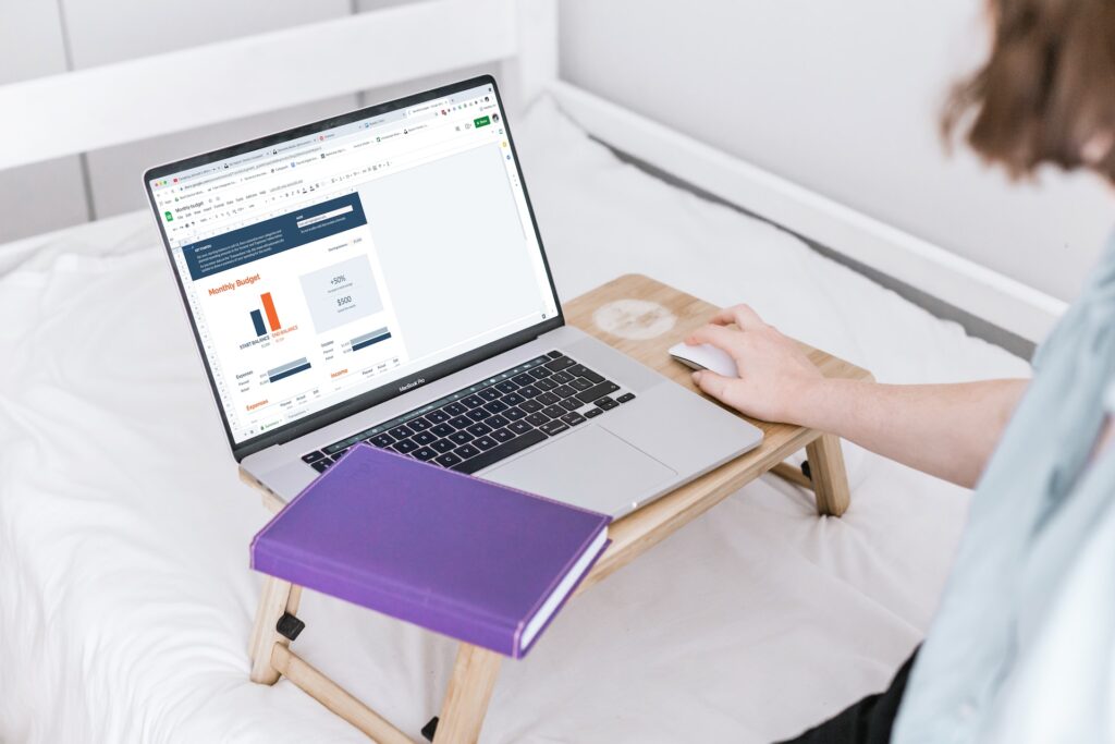 A woman using a silver Macbook Pro on planning a monthly budget