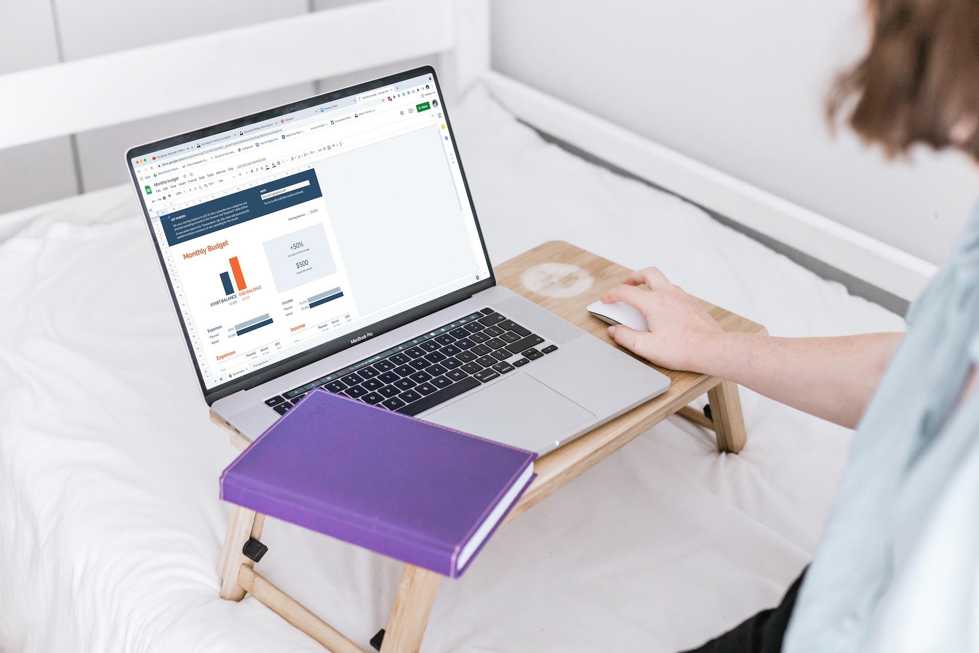 A woman using a silver Macbook Pro on planning a monthly budget