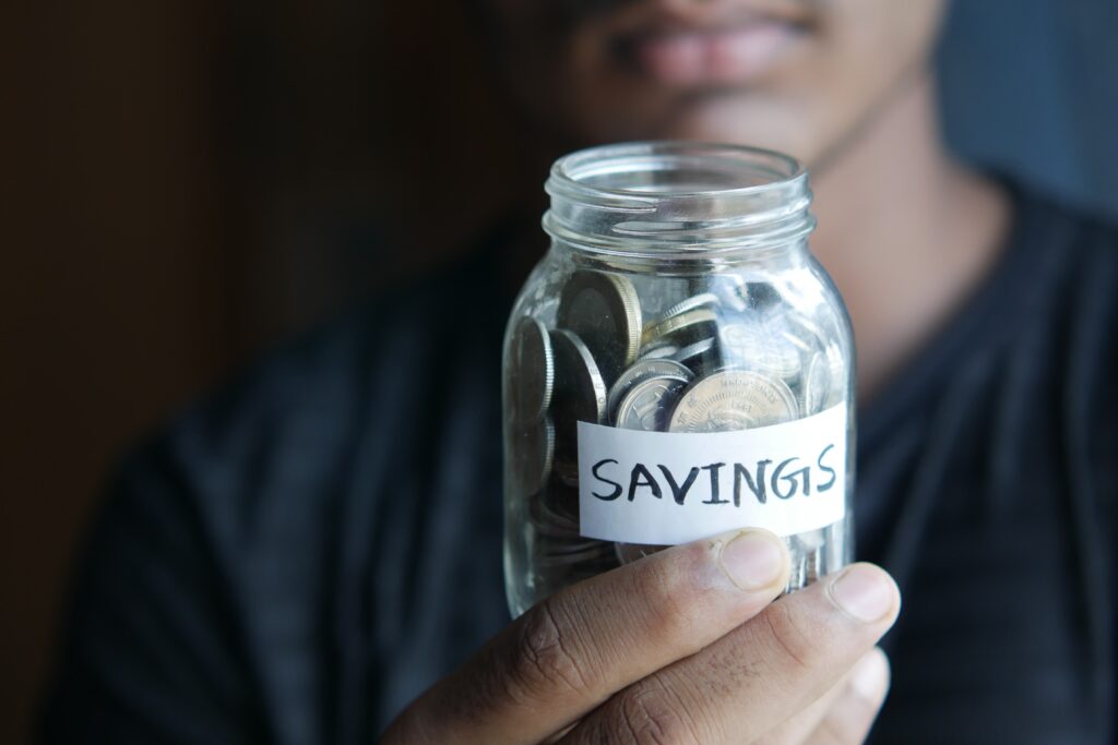 A man holding a jar of coins labeled as savings