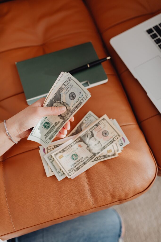 A woman holding money and some dollars on the leather sofa
