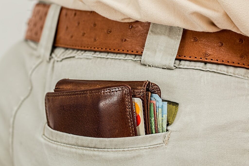A folded wallet with money and card on the back pocket of a man