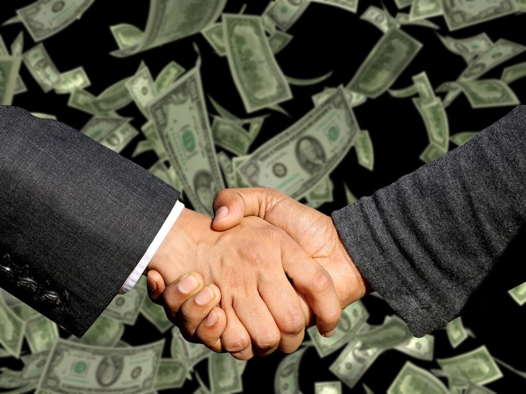 Cropped shaking hands of a two man with dollar bills falling on the background