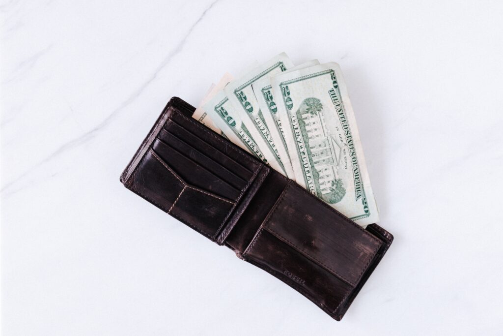 An open black wallet with some money bills on it