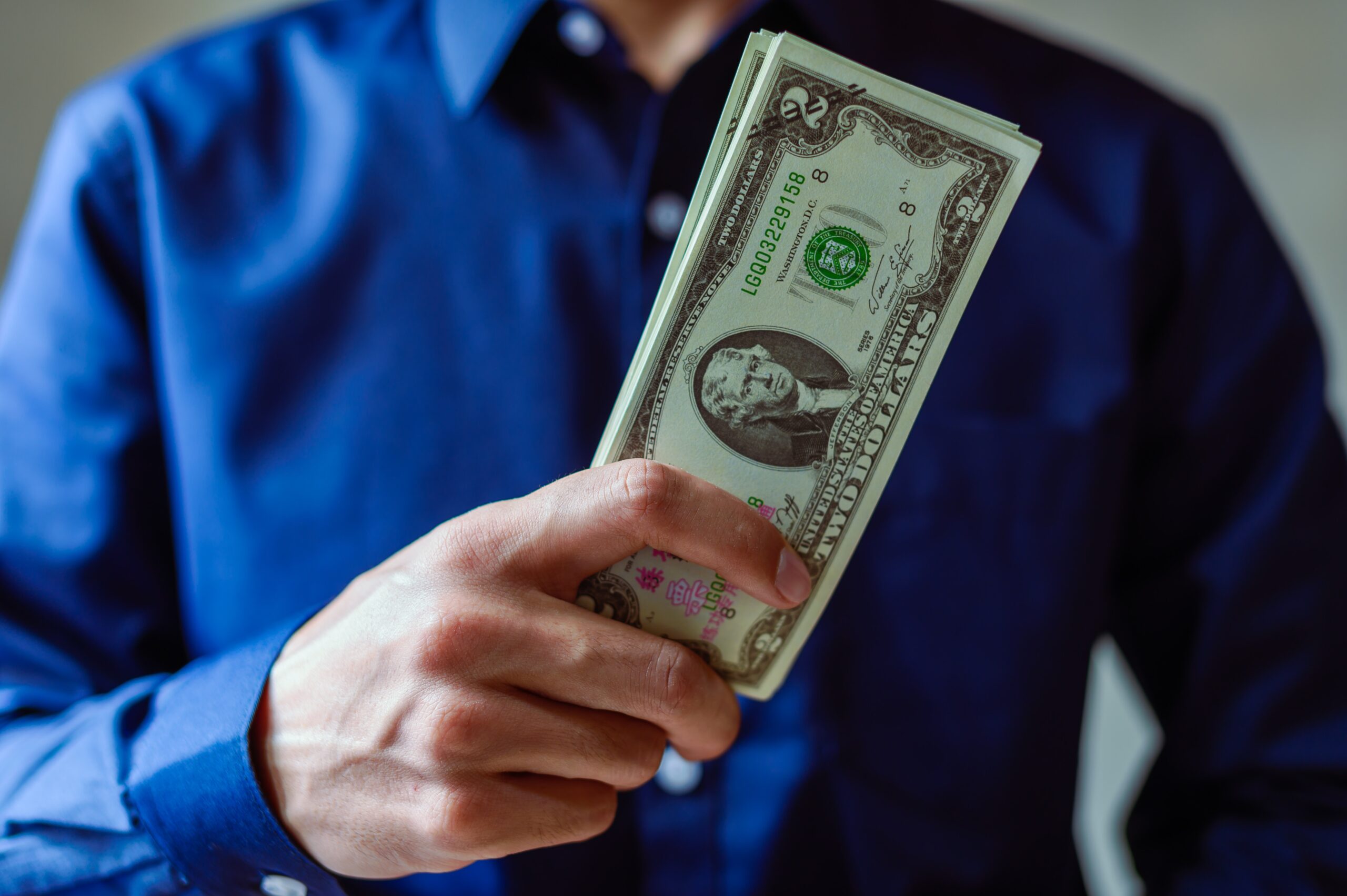 A man wearing blue long sleeves showing money bills
