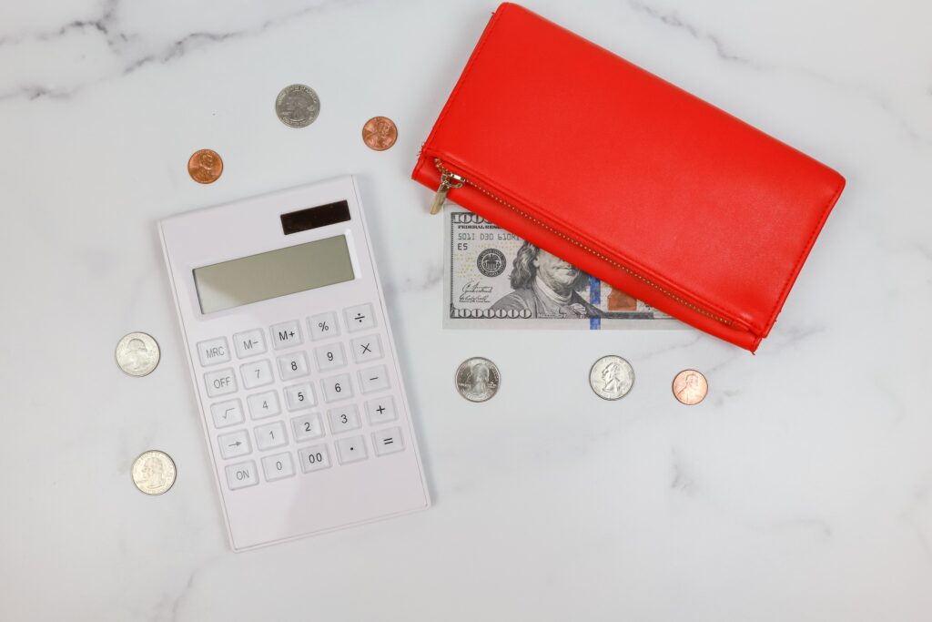 An image of a red wallet, a dollar bill, coins and a calculator