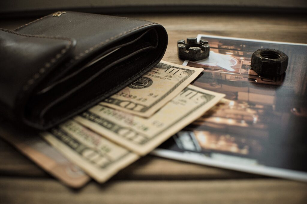An image of a leather wallet with dollar bills and a photo