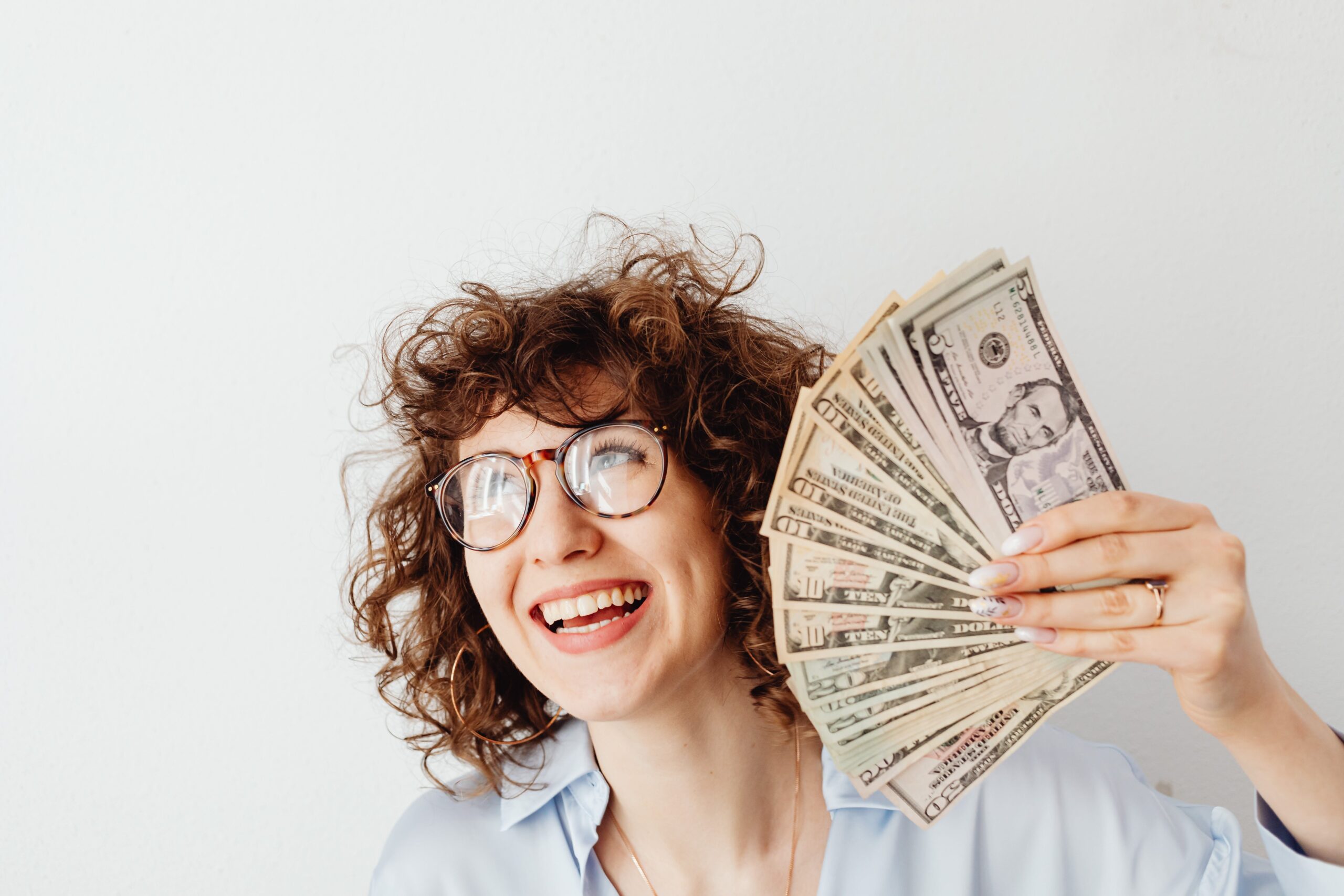 A woman smiling while flaunting her dollar bills