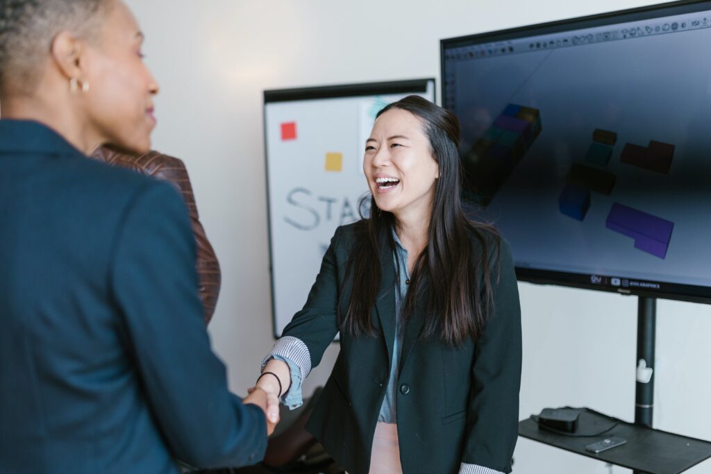 Two women happily shaking hands after a business presentation