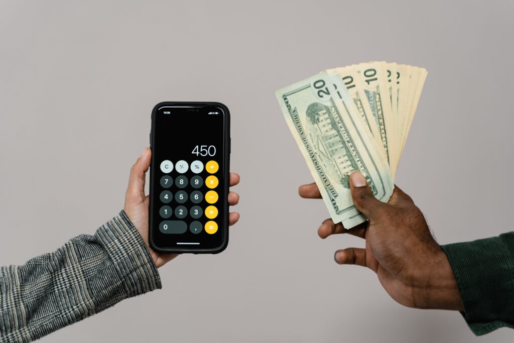 A woman holding a phone with its calculator app open on the left and a man holding dollar bills on the right